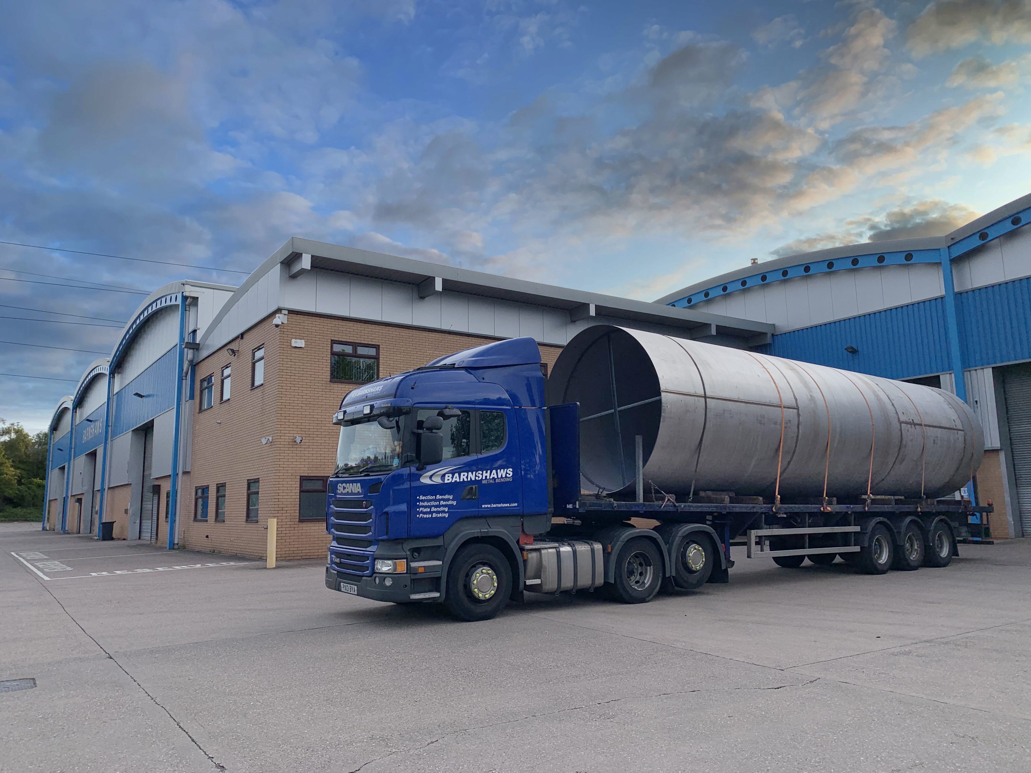 Barnshaws lorry with a large metal tube on the back parked outside an industrial unit