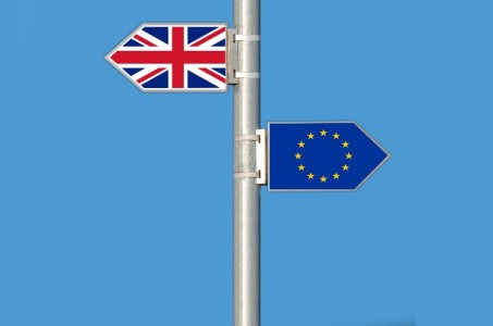 A Union Jack and European Union flag in the shape of arrows pointing in opposite directions against a blue sky background.