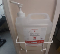 A large pump action container of alcohol hand gel attached to a wall