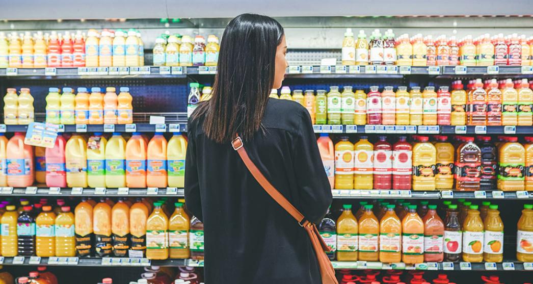 Young woman in supermarket looking at a choice of fruit juices