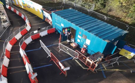 Mollies Café catering unit in what looks like a blue shipping container on a construction site with red and white barriers outside it.