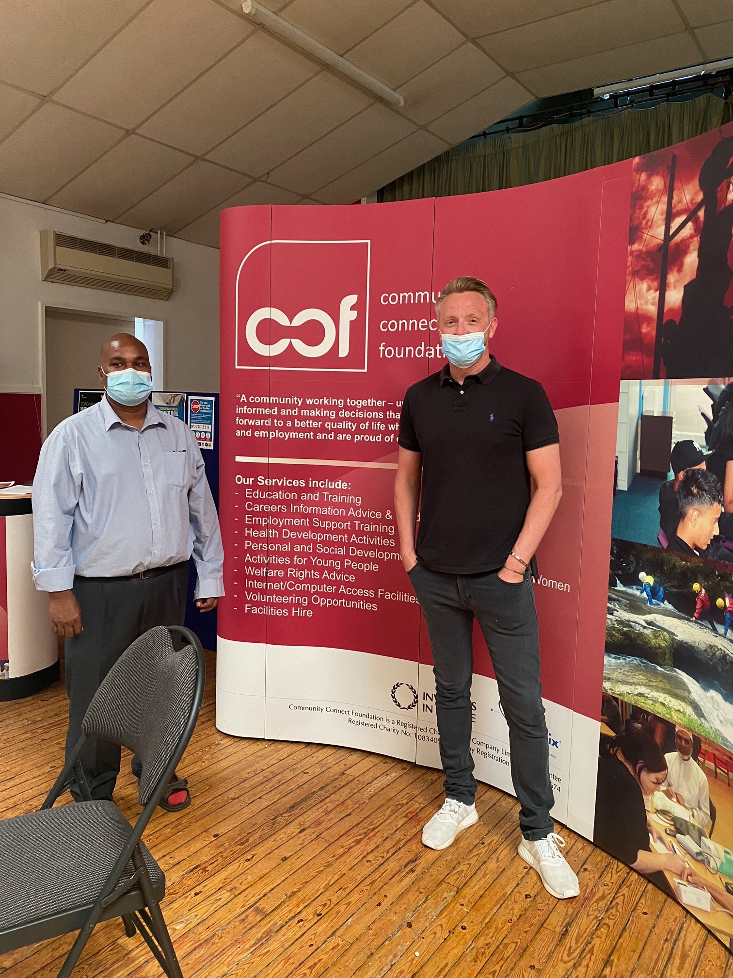 Paul of KMB with Soyfur from Community Connect Foundation both wearing masks, standing in front of a CCF banner