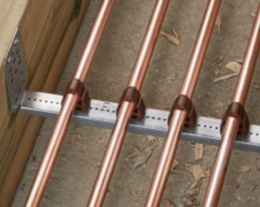 Four thin copper pipes held in place in a wooden channel with an aluminium clip system.