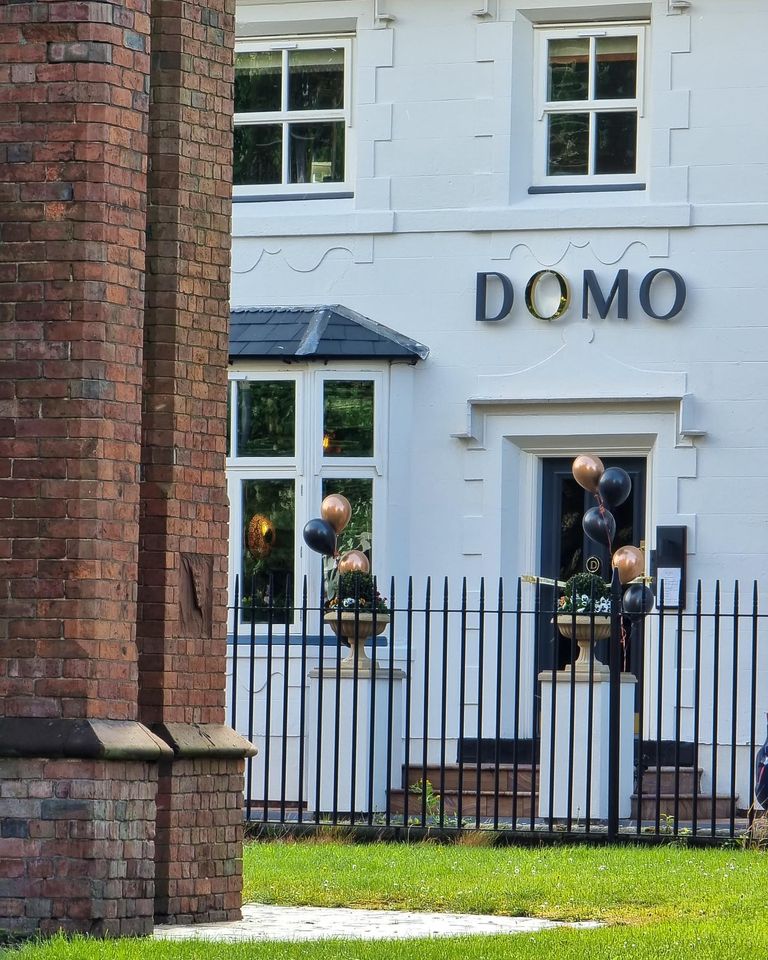 Domo Boutique Hotel exterior - a white brick building with a black railing in front of it