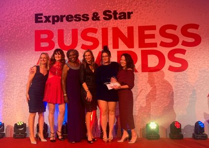 A group of women on a stage with a banner saying Express & Star Business Awards behind them