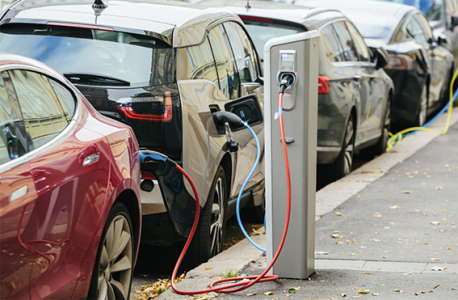 Close up of two electric cars plugged into a charger