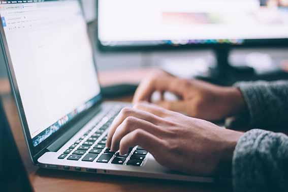 Close up of hands typing on a laptop keyboard