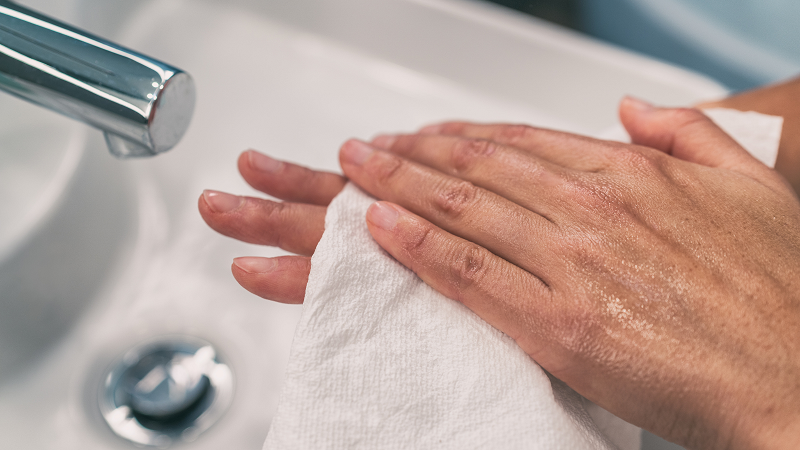 Medium to dark skin tone slim hands being washed with a cloth in a sink