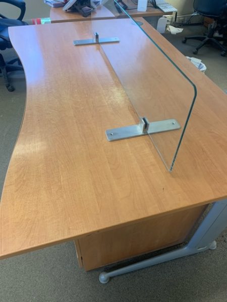 Glass screen fixed to an office desk