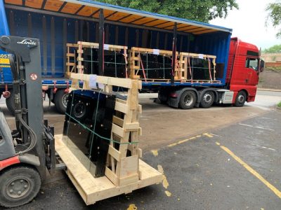 A forklift truck loading pallets onto an open-sided lorry