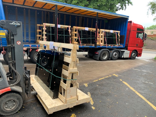 A forklift truck loading pallets onto an open-sided lorry