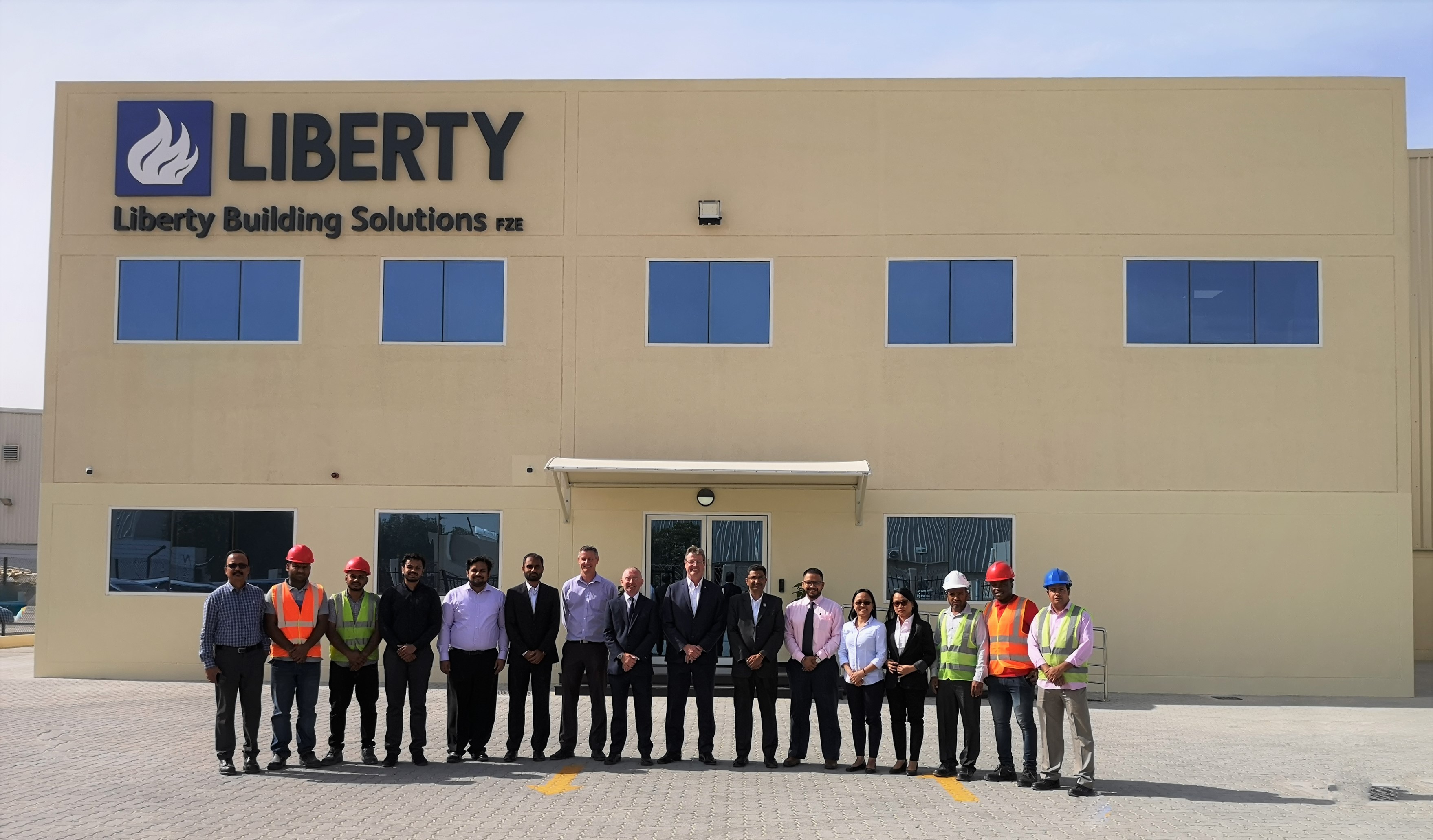 A group of people standing in a line in front of a cream building with a Liberty sign on it.