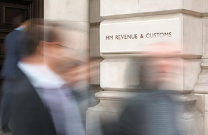 Blurred image of people outside a building with the words HM Revenue & Customs on it