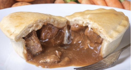 A meat pie, sliced in half, with the contents spilling out onto the plate.