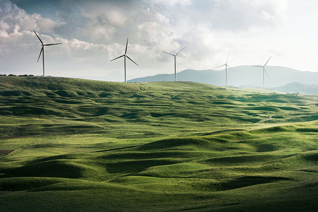 Wind turbines in the distance with green rolling hills in the foreground