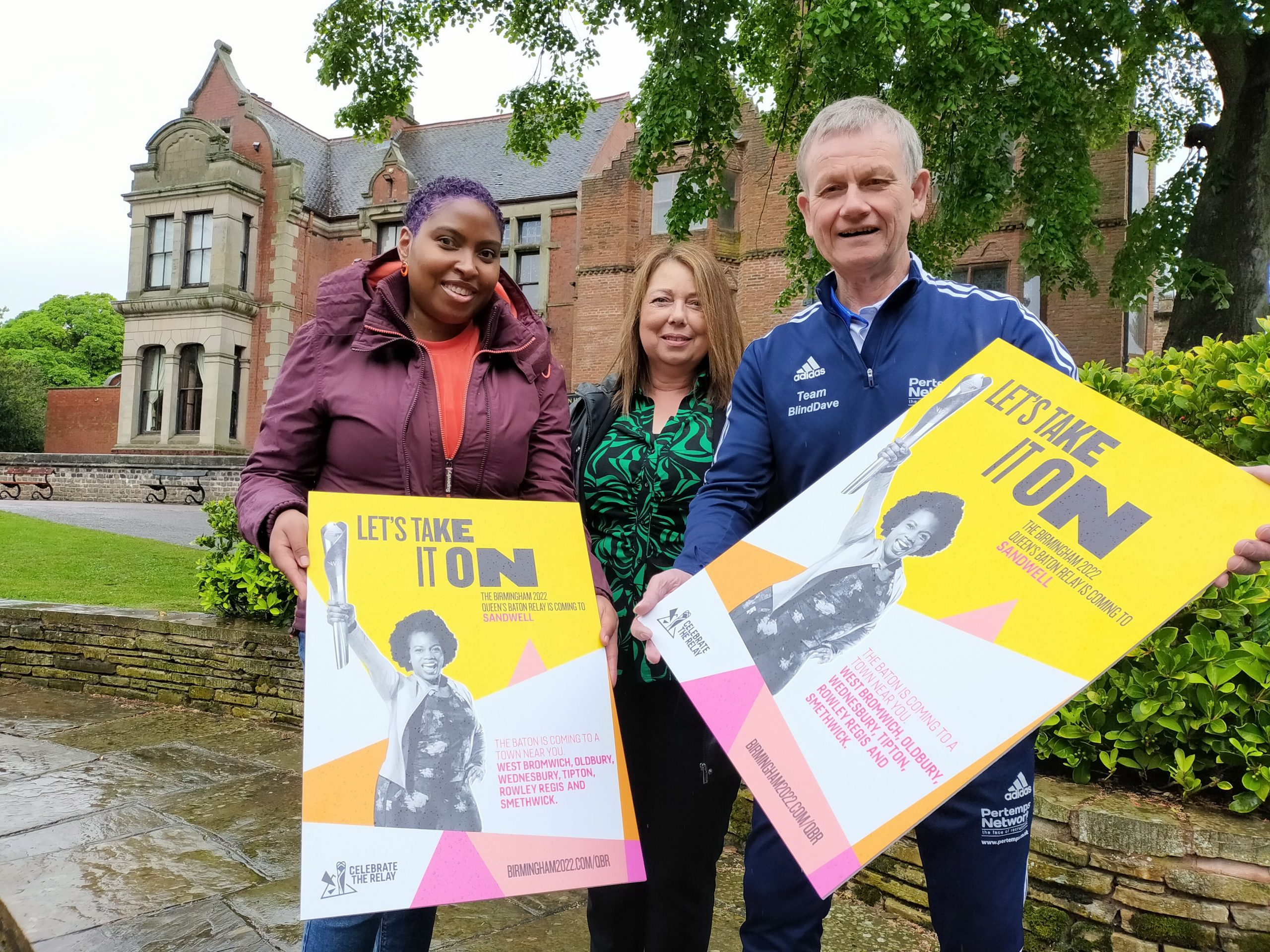 Three people holding posters standing in front of Haden Hill House