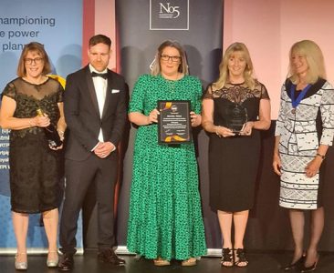 Five people staying on a stage having received an award