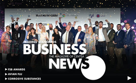 A group pf people standing on a stage with text 'Trading Standards Business News' across the front