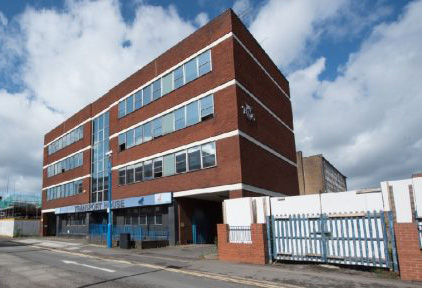 A red brick office block with a cloudy sky behind it.