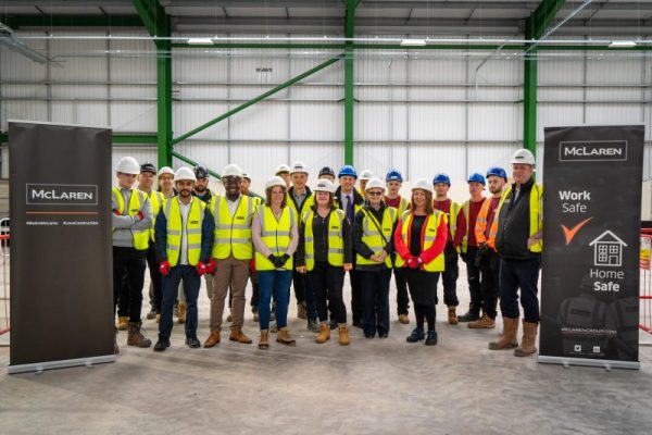 Around 21 people in hard hats and high vis jackets, smiling