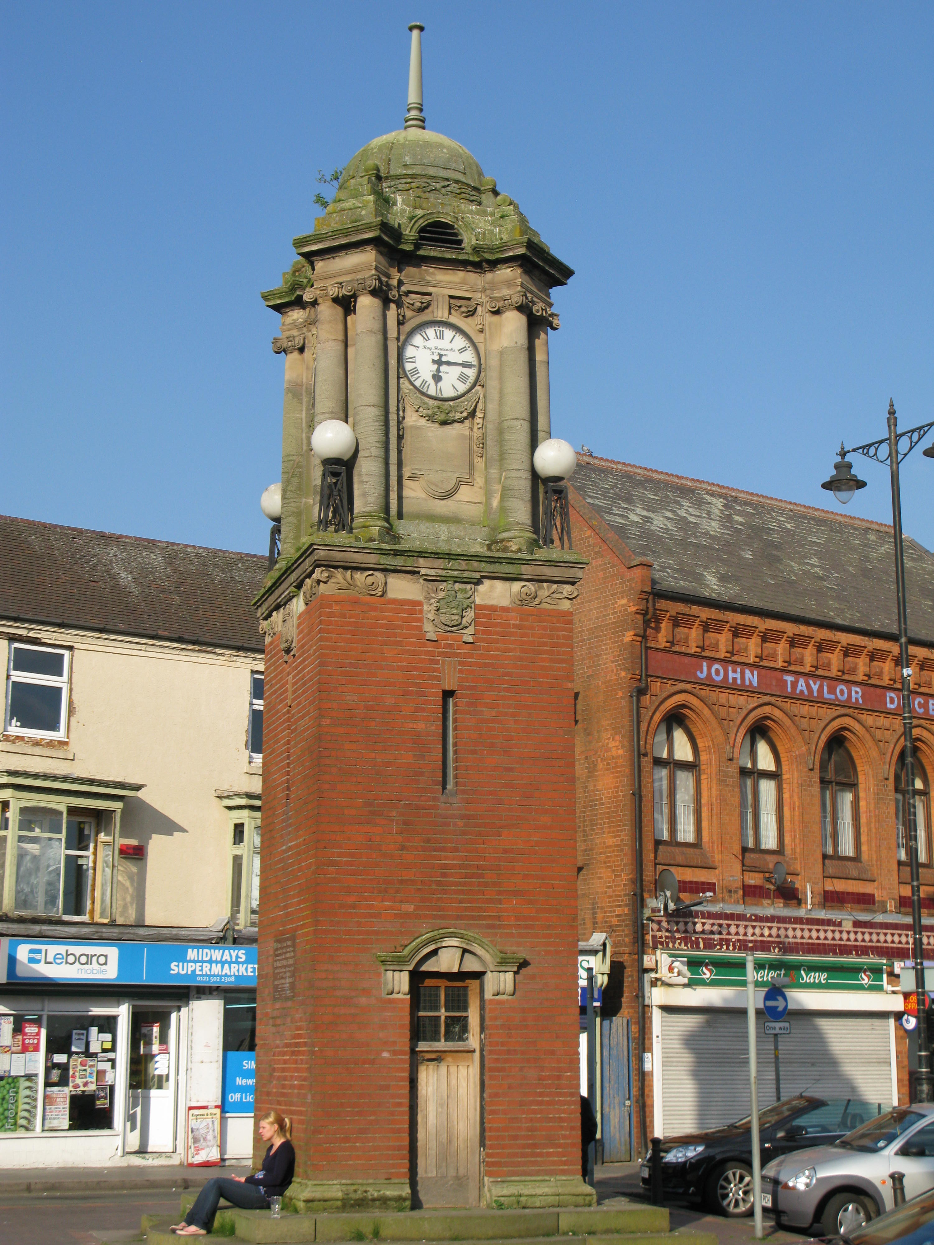 A clock tower with buildings behind it.