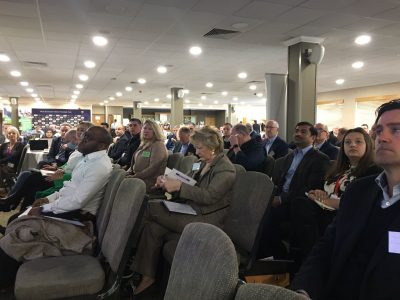 side on photo of many people watching someone present at the meet the buyer event