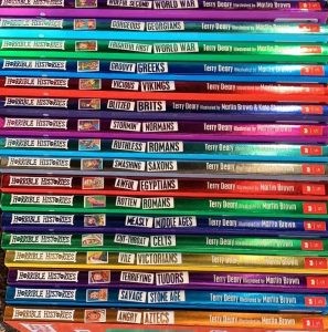 A close up of a pile of books neatly stacked with colourful spines