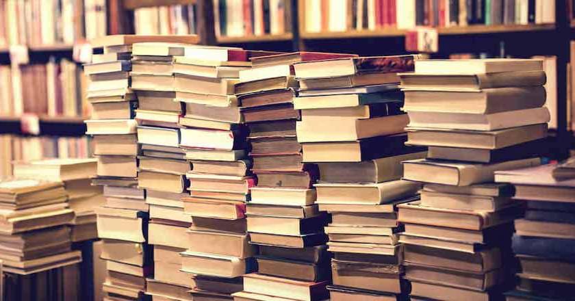 Piles of books in front of shelves full of books