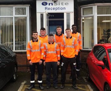 A group of apprentices wearing orange high vis jackets standing infront of OnSite reception