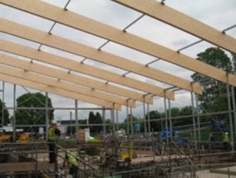 The a metal framework for a building with wooden planks across the roof.