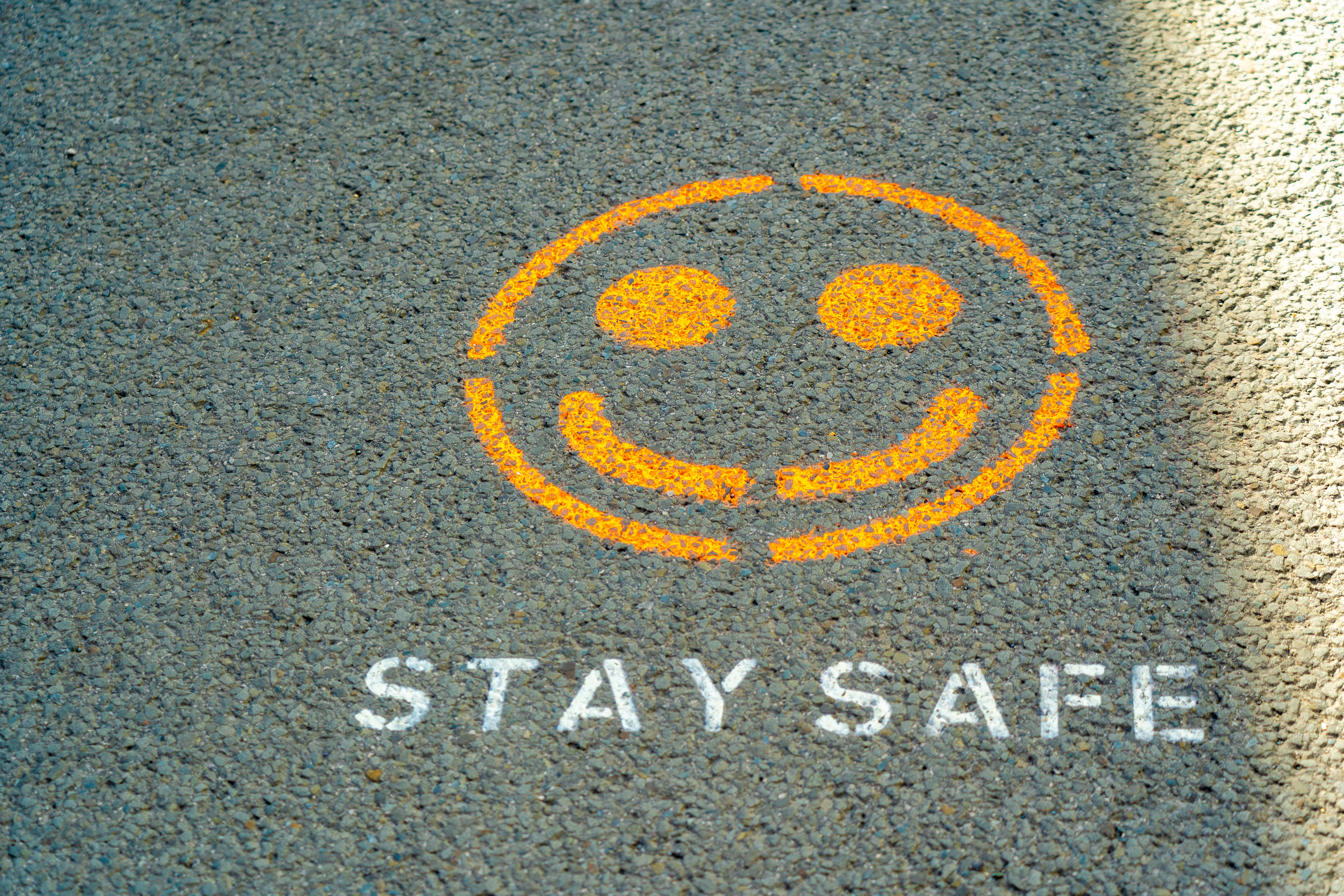 A smiley face and the words 'Stay Safe' spray painted onto the ground