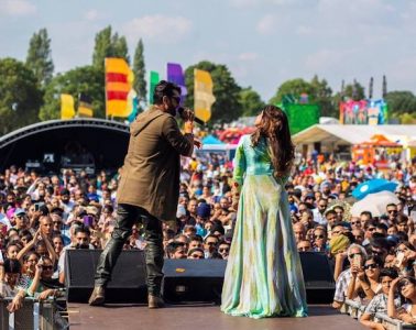 Two people performing on a stage to a large crowd