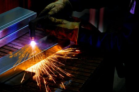 Close up of the gloved hands of a steel worker using a blow torch creating sparks on metal