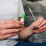 A close up of a person holding a swab and a test tube