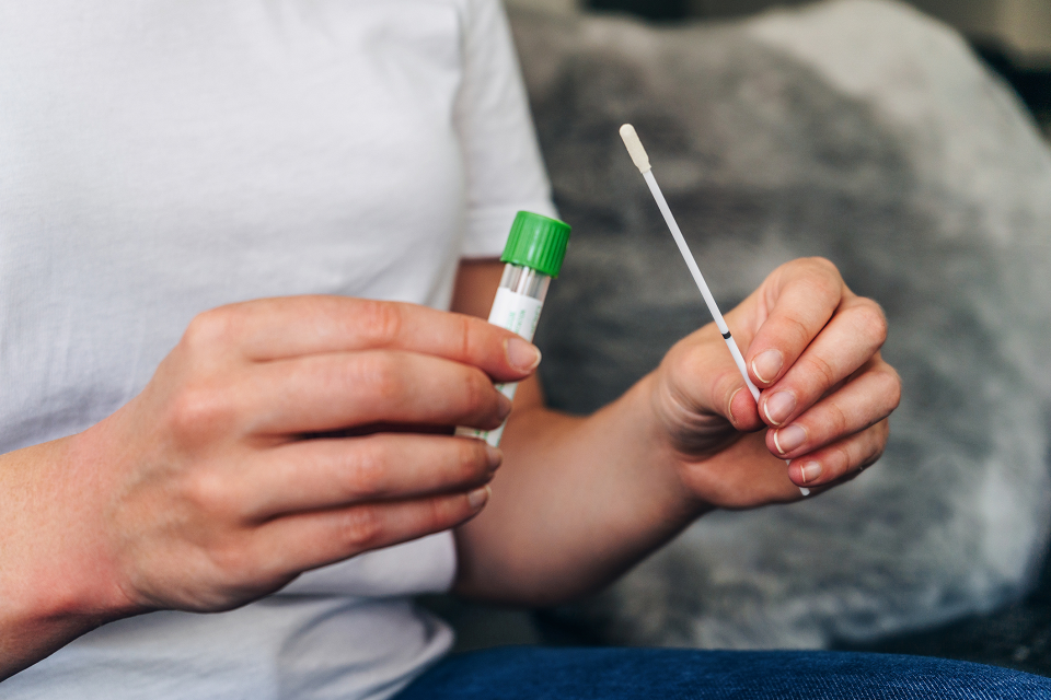 A close up of a person holding a swab and a test tube