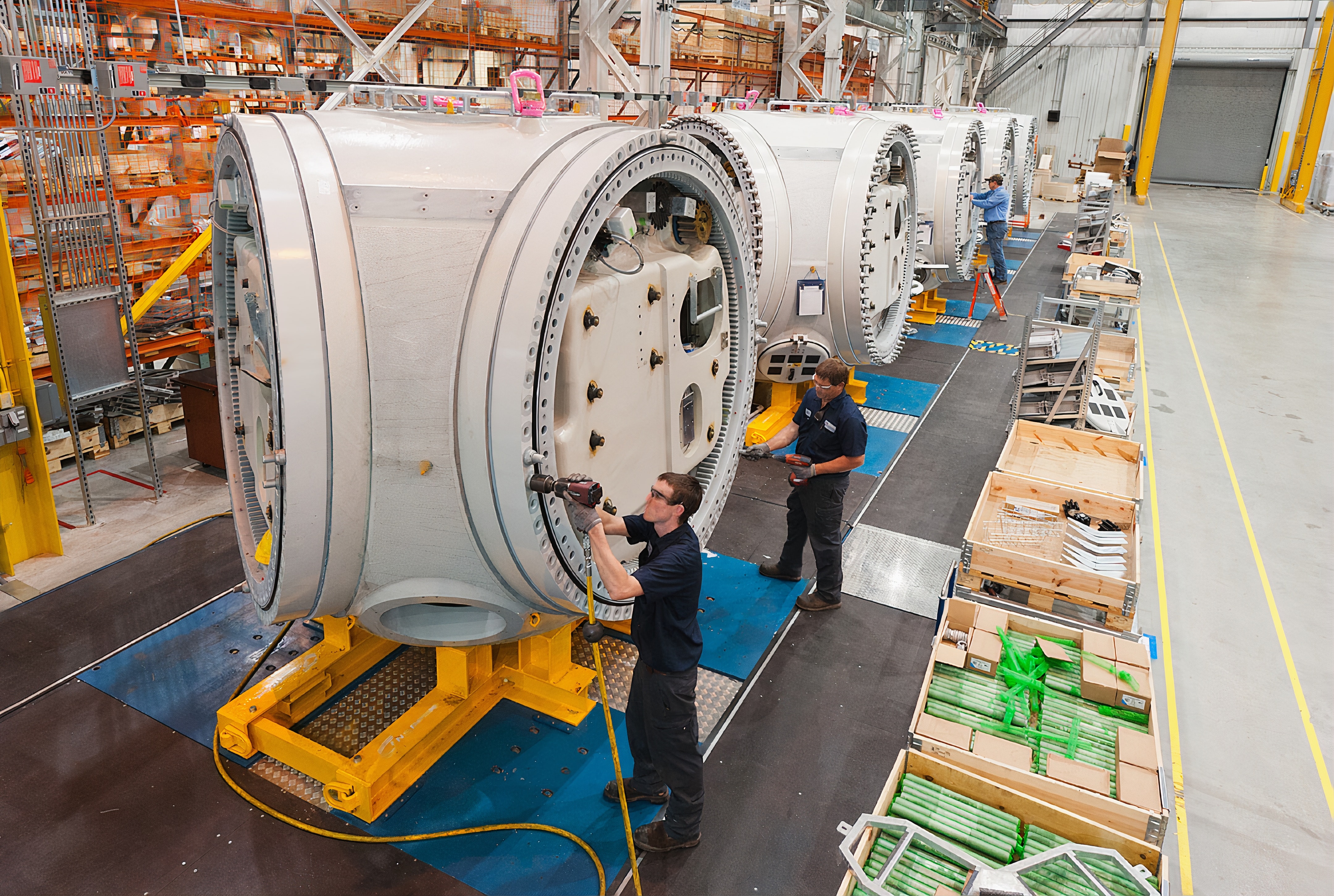 Three people working in a large factory setting.